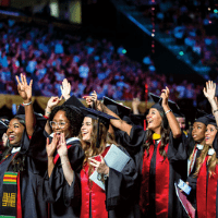 seniors at graduation ceremony with hands in air