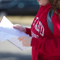 student in Md sweatshirt holding papers