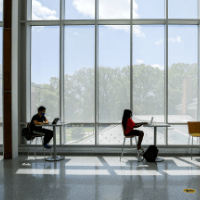 students at desks in front of large windows