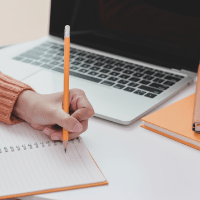 hand holding pencil on notepaper